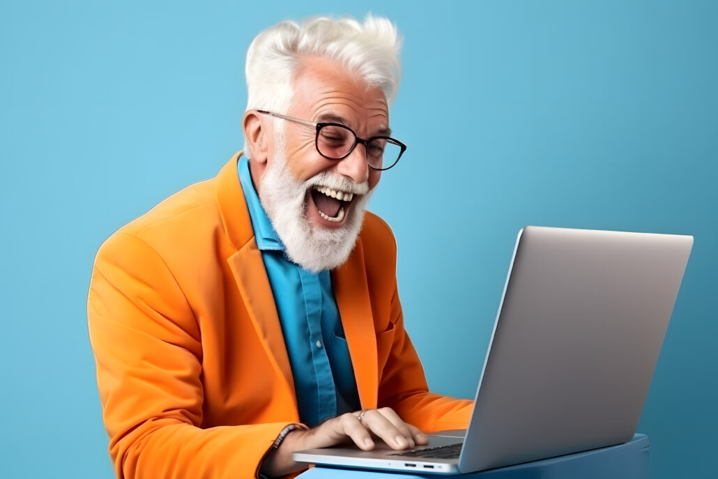 Happy smiling elderly bearded man using laptop on blue background